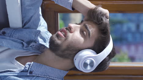 Vertical-video-of-Unhappy-man-listening-to-music-with-headphones.